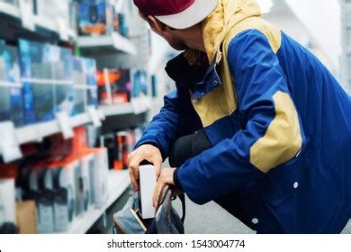 close up consumer thief's hands putting the new gadget in the pocket in the store