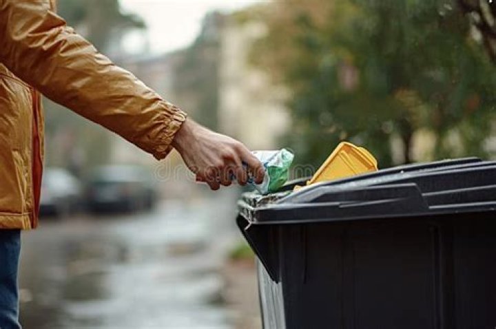 man throwing away black trash back