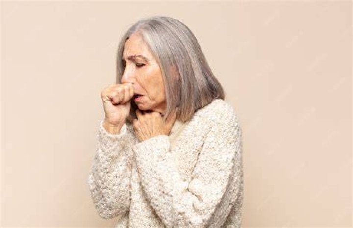 Middle aged woman coughing in the street