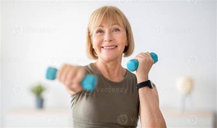 Strong senior woman doing exercises with dumbbells indoors.